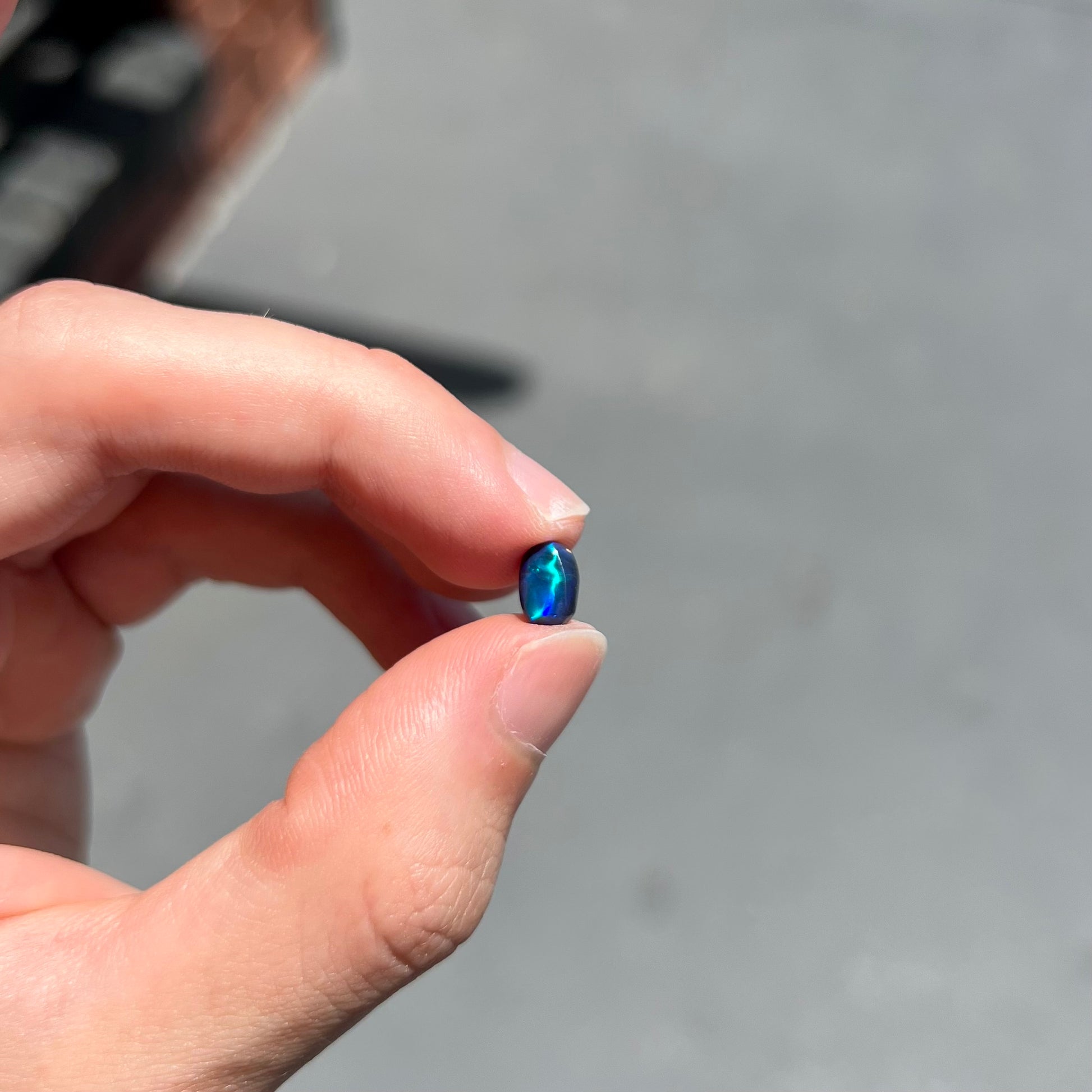 A loose black opal from Lightning Ridge, Australia.  The opal displays a blue cat's eye pattern.