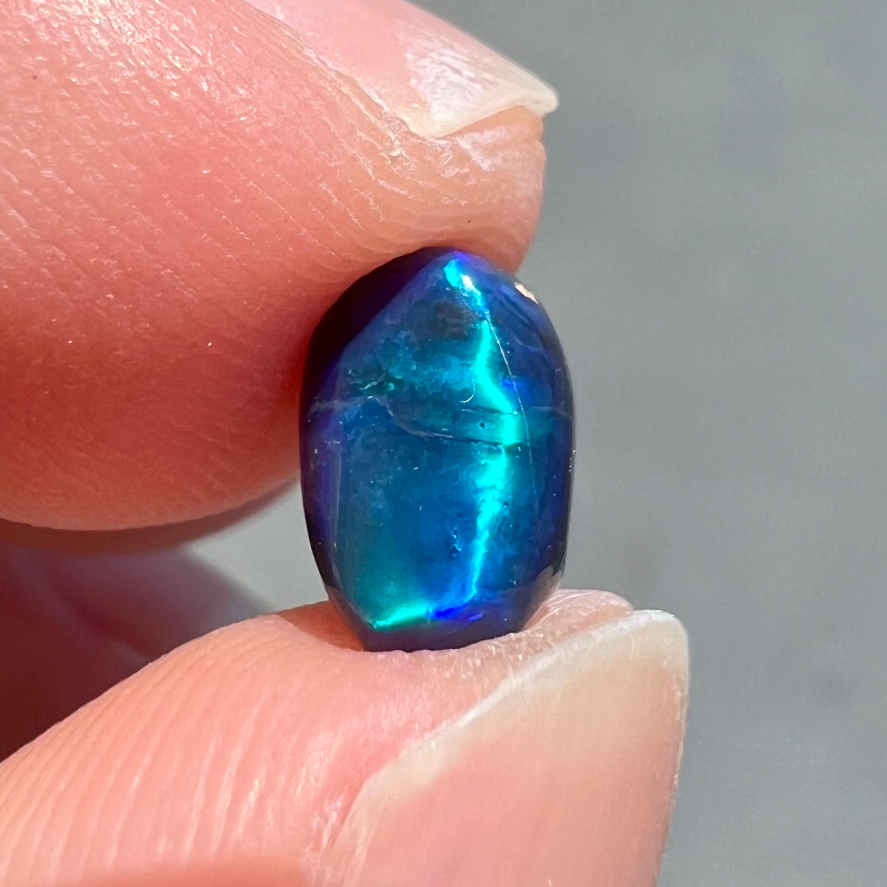 A loose black opal from Lightning Ridge, Australia.  The opal displays a blue cat's eye pattern.
