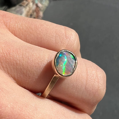 A yellow gold solitaire ring set with a natural Australian cat's eye opal stone.