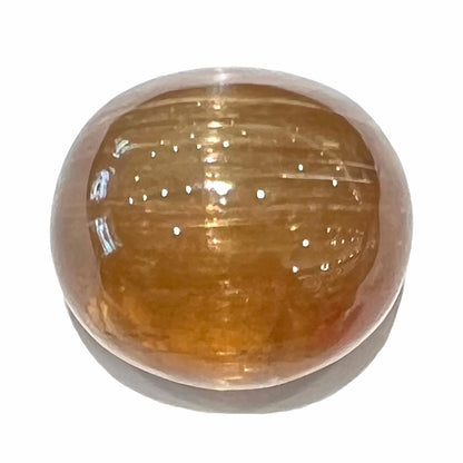A loose, golden brown cat's eye dravite tourmaline gemstone.  The stone is cut into an oval shaped cabochon and weighs 43.45 carats.