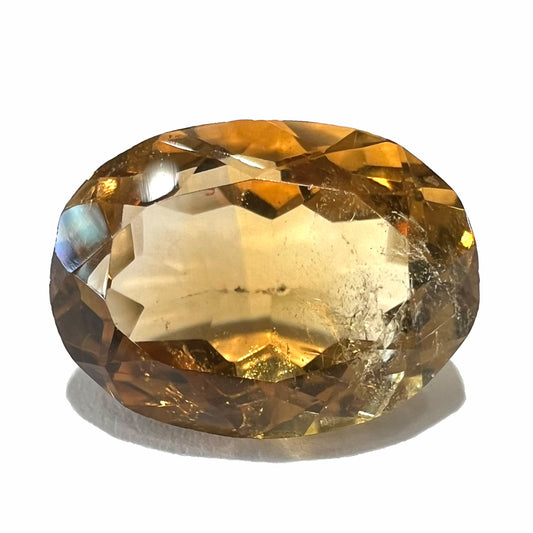 A loose, oval cut citrine gemstone.  The stone is heavily included and roughly cut.