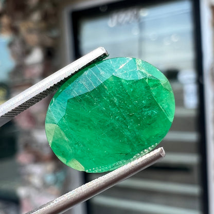 A loose, faceted oval cut commercial grade emerald stone.