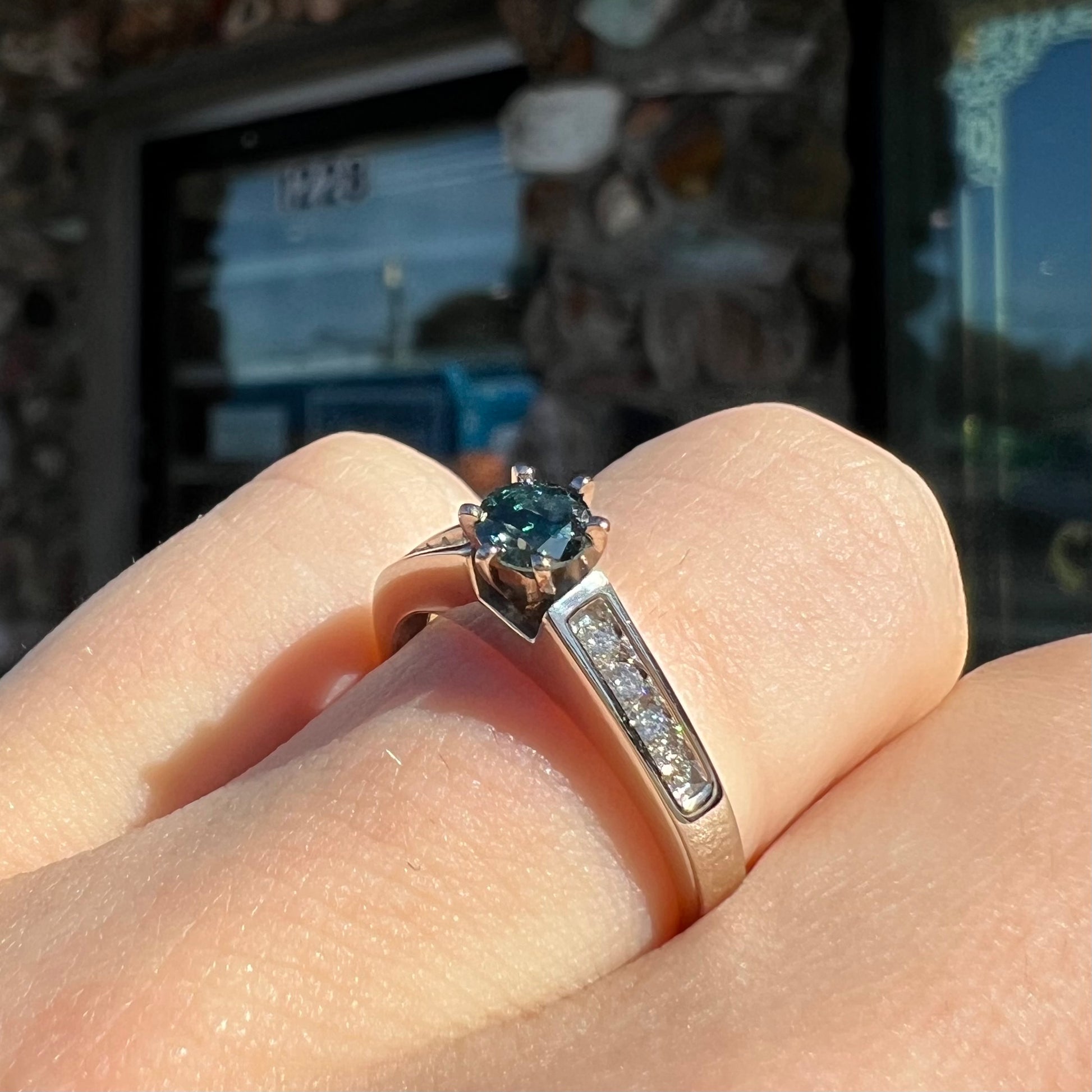 A ladies' white gold engagment ring set with a round brilliant blue diamond and channel set diamond accents.