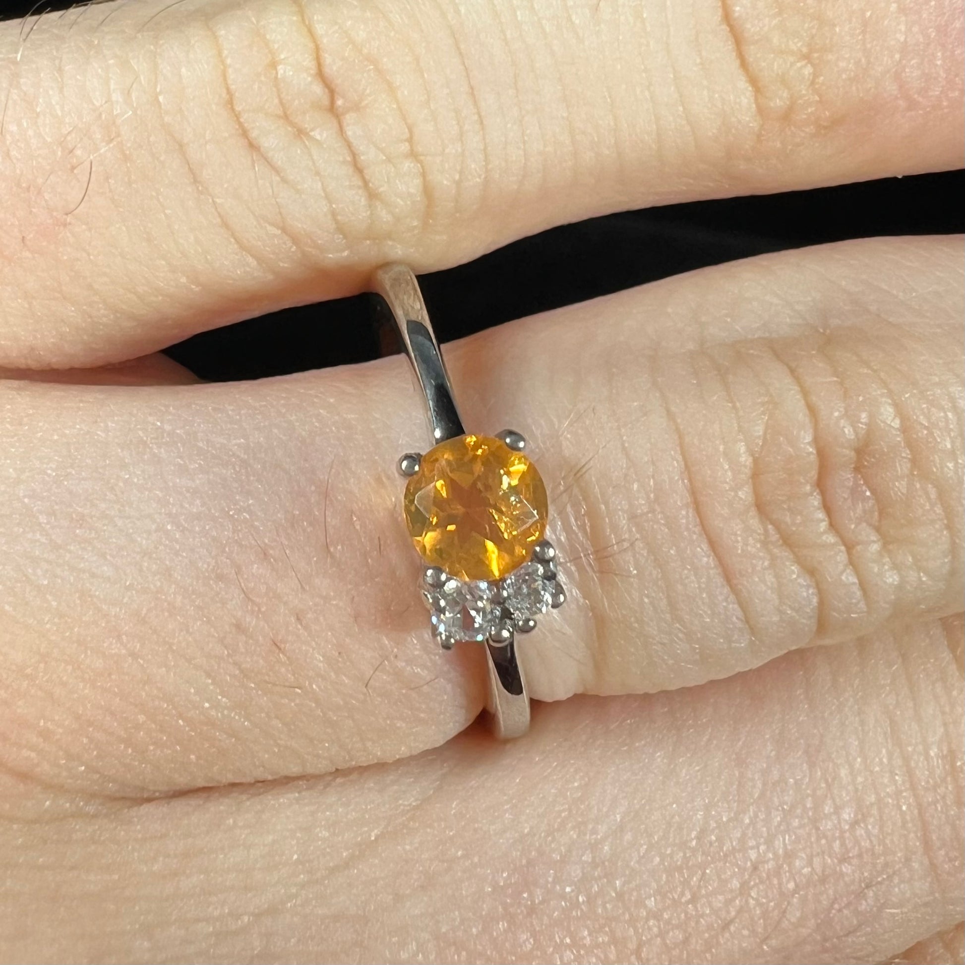 A ladies' sterling silver ring set with a faceted round cut fire opal and white zircon accents.