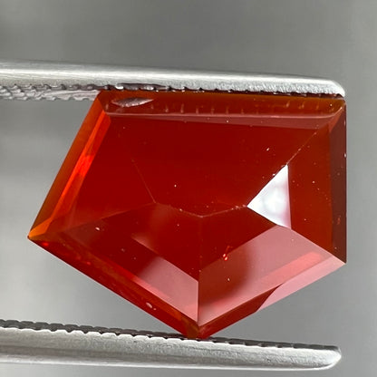 A loose, faceted freeform cut Mexican fire opal gemstone.  The stone is a cherry red color.