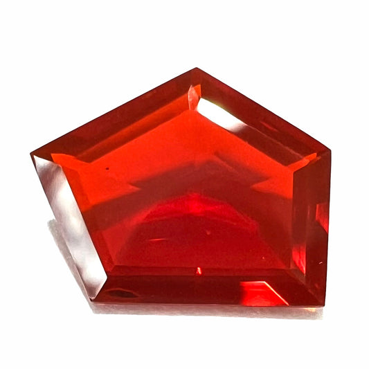 A loose, faceted freeform cut Mexican fire opal gemstone.  The stone is a cherry red color.