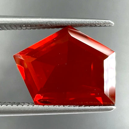 A loose, faceted freeform cut Mexican fire opal gemstone.  The stone is a cherry red color.