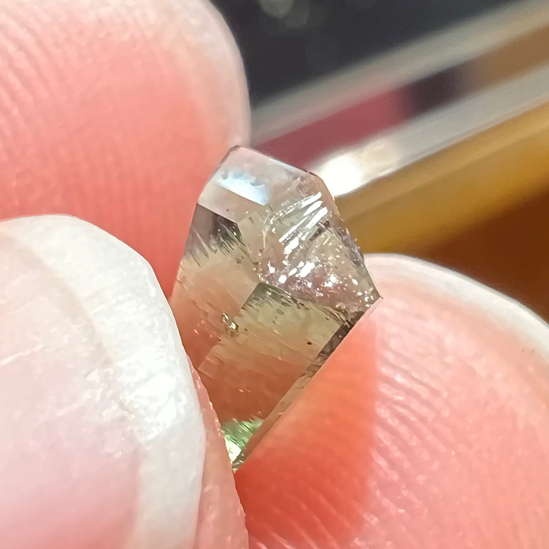 A loose, shield cut, natural moldavite gemstone.  The stone has a small chip in the top corner facet.