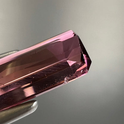 A loose, modified emerald cut tricolor tourmaline.  The stone transitions from pink to light pink to white colors.