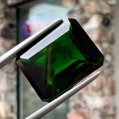 A large, emerald cut chrome diopside gemstone.  The gem is dark green color.