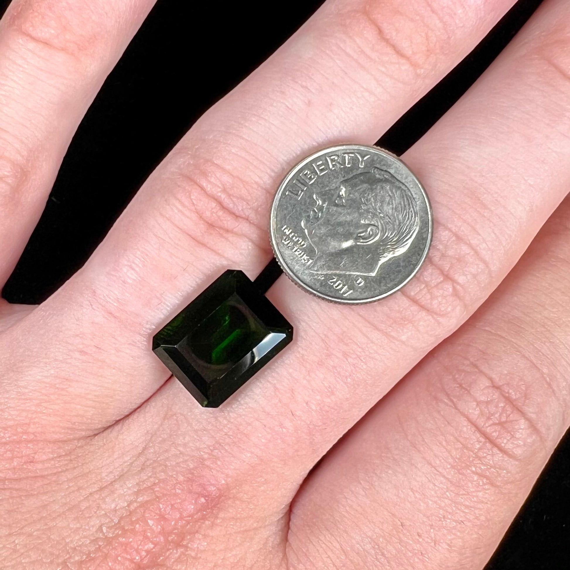 A large, emerald cut chrome diopside gemstone.  The gem is dark green color.