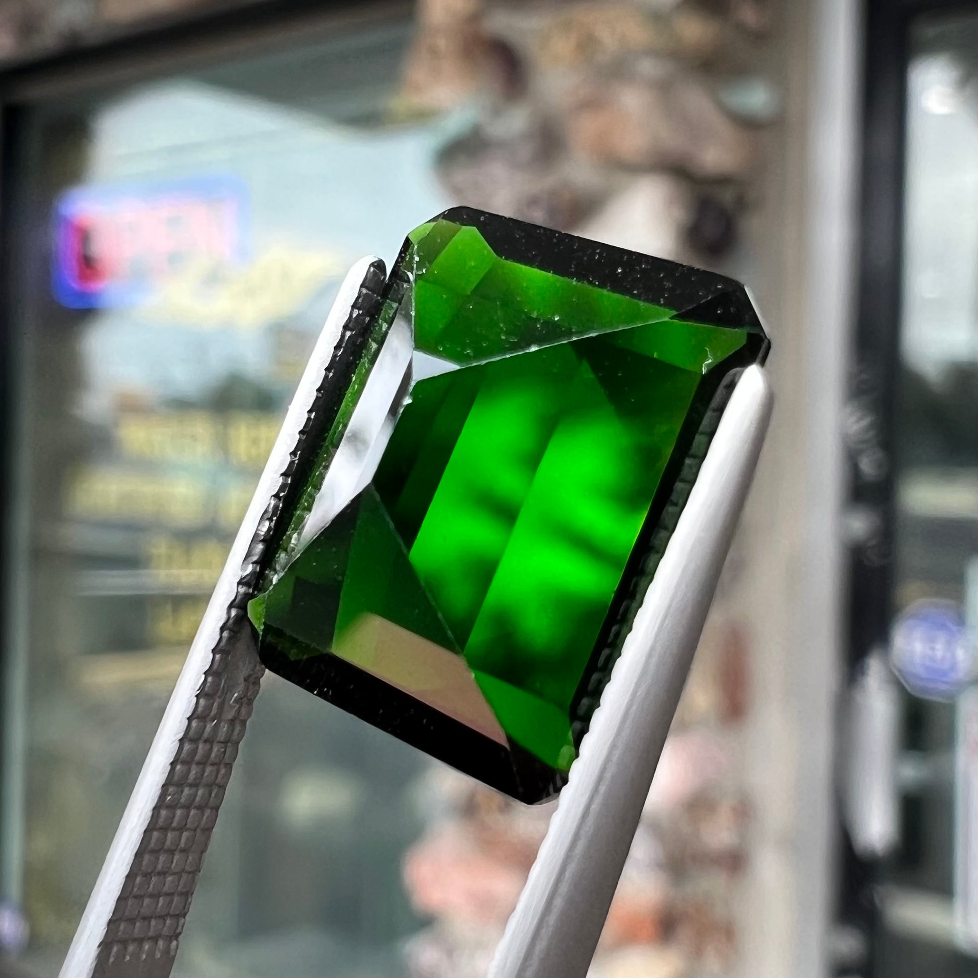 A large, emerald cut chrome diopside gemstone.  The gem is dark green color.