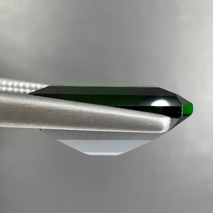 A large, emerald cut chrome diopside gemstone.  The gem is dark green color.