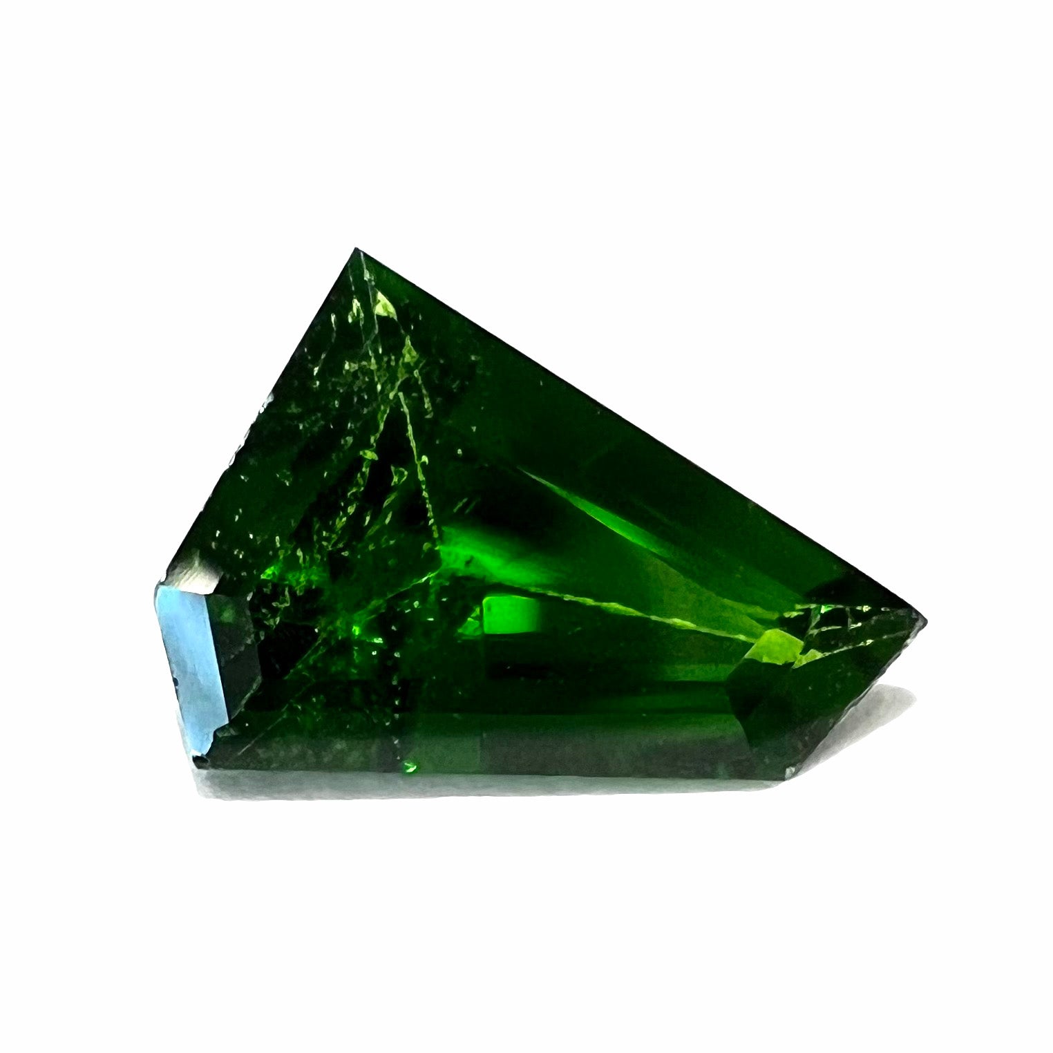 A freeform shield cut chrome diopside gemstone that weighs 1.43 carats.