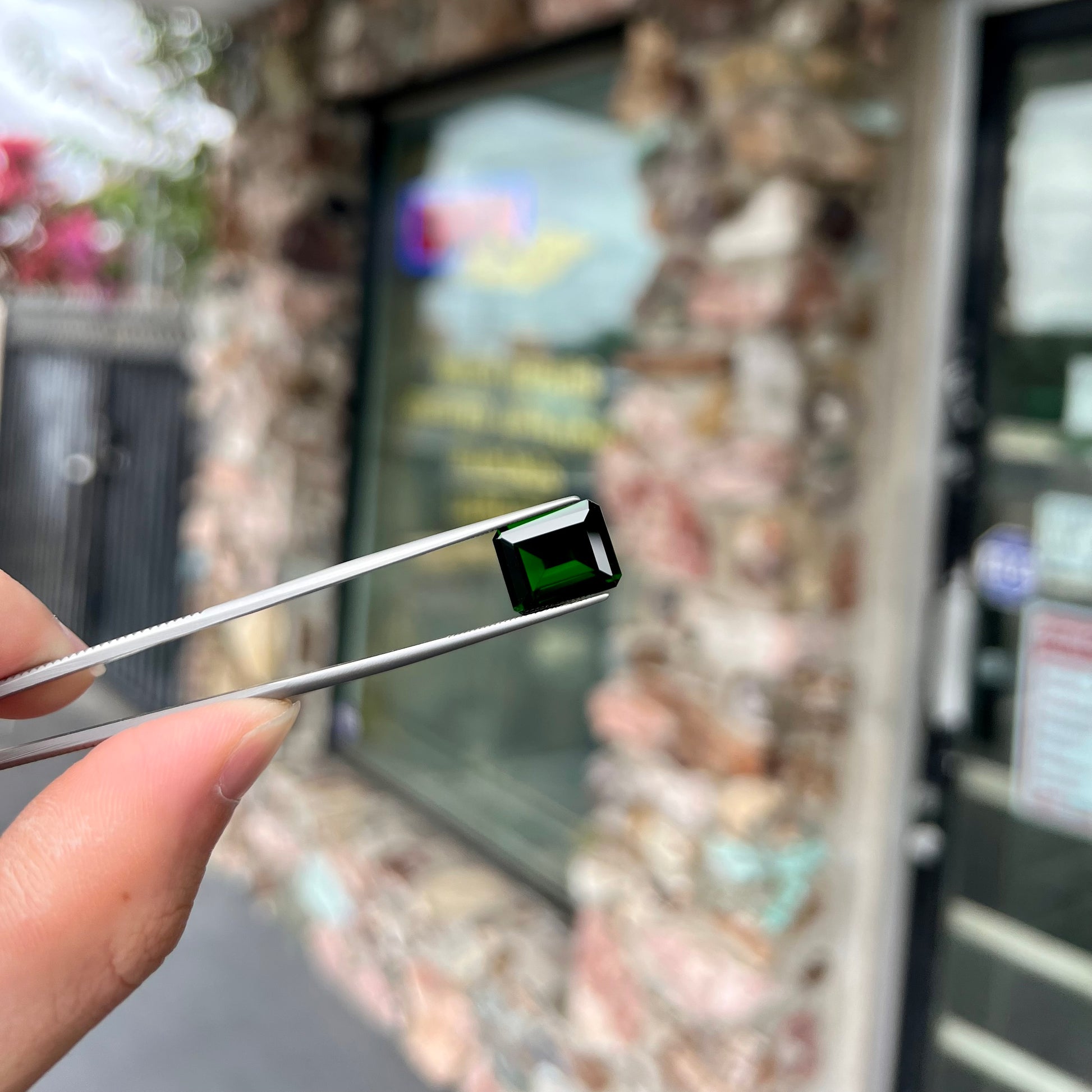 A large, emerald cut chrome diopside gemstone.  The gem is dark green color.