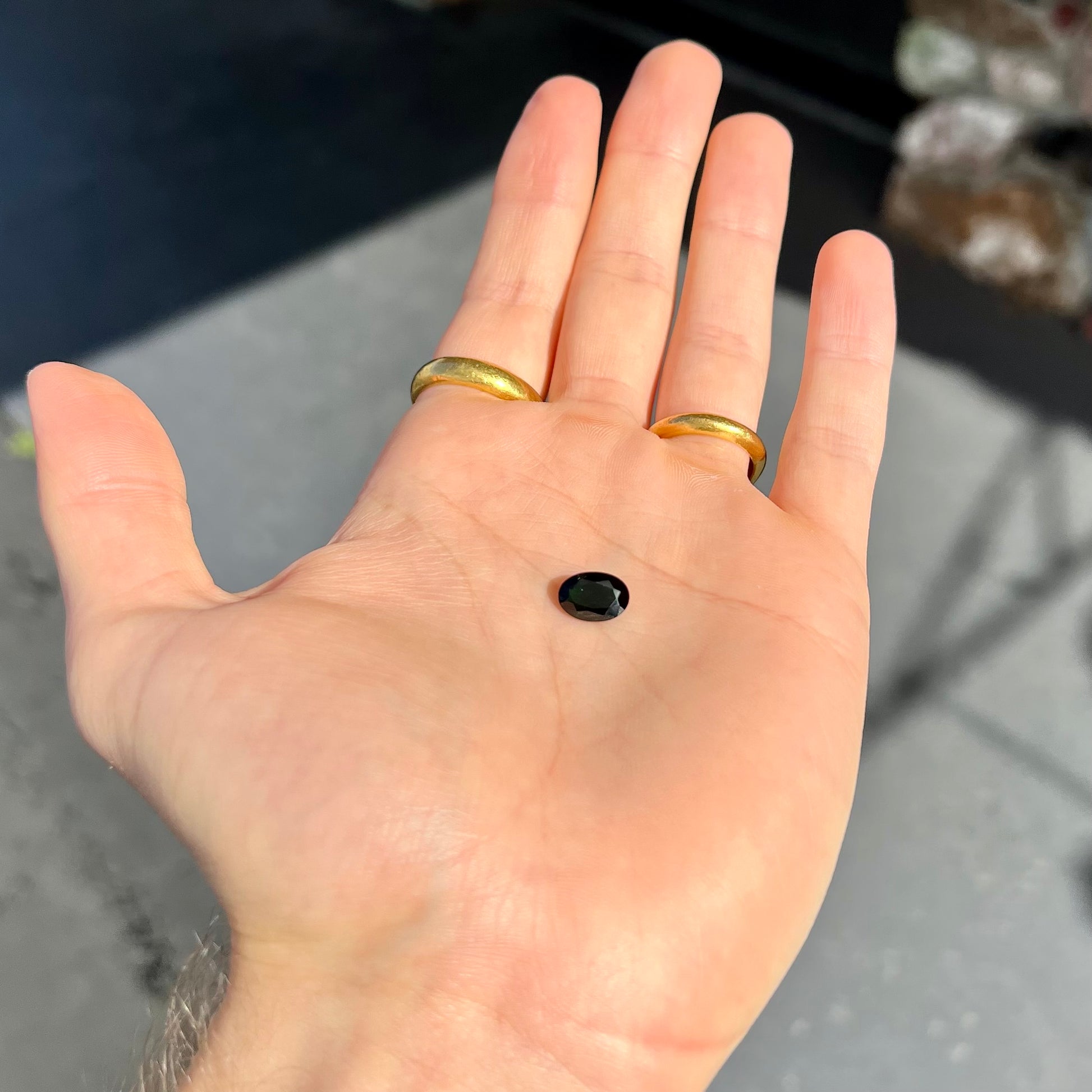 A faceted oval cut chrome tourmaline gemstone.  The stone is dark green.