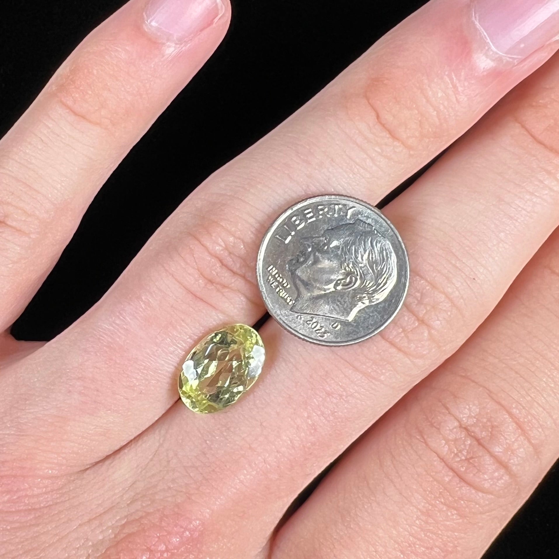 A loose, faceted oval cut chrysoberyl gemstone.  The stone is a greenish yellow color.