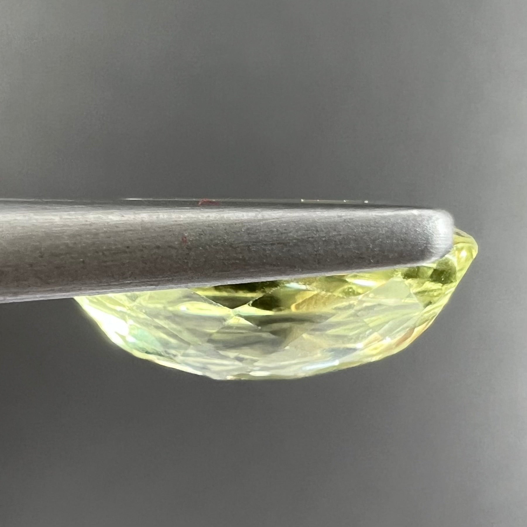 A loose, faceted oval cut chrysoberyl gemstone.  The stone is a greenish yellow color.