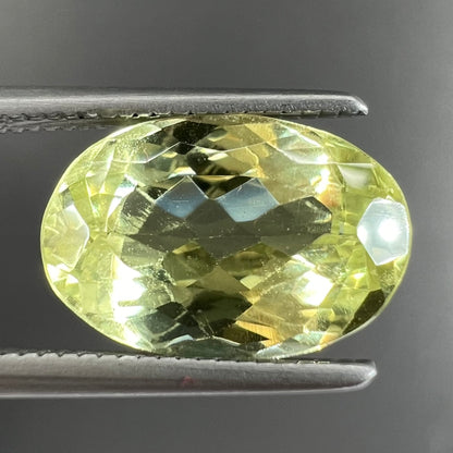 A loose, faceted oval cut chrysoberyl gemstone.  The stone is a greenish yellow color.