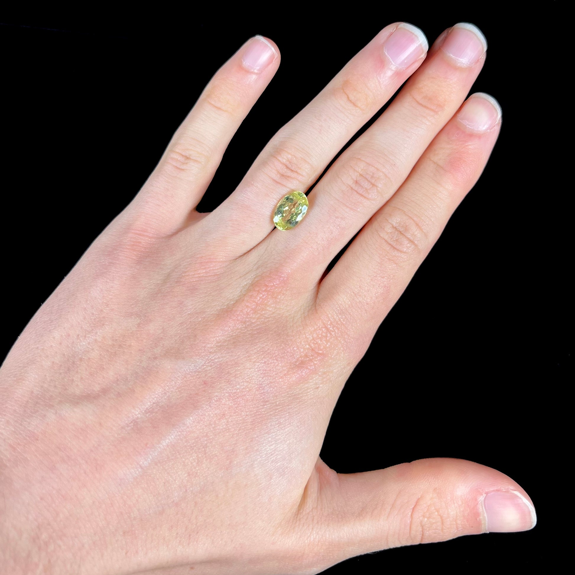 A loose, faceted oval cut chrysoberyl gemstone.  The stone is a greenish yellow color.