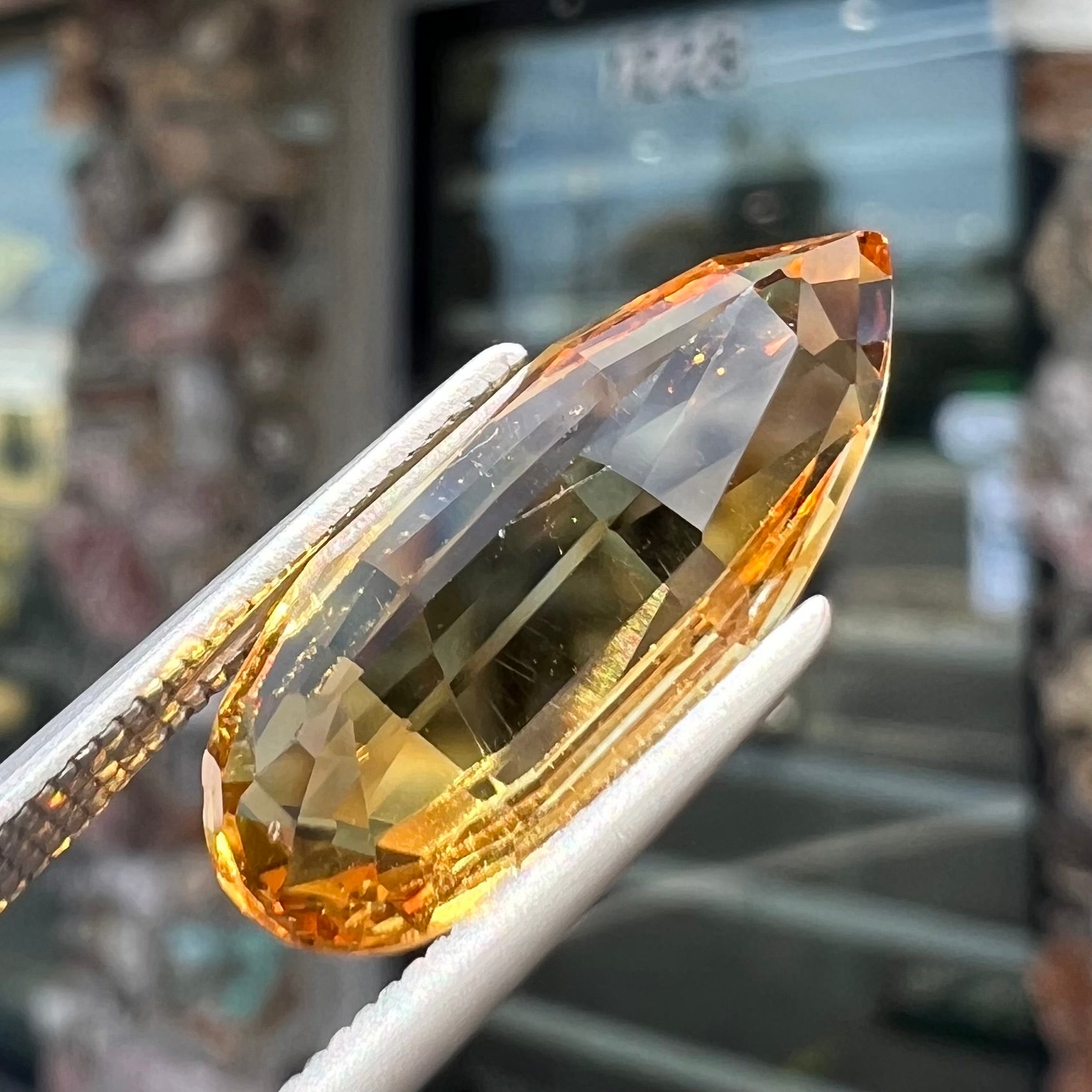 A loose, faceted briolette cut citrine gemstone.