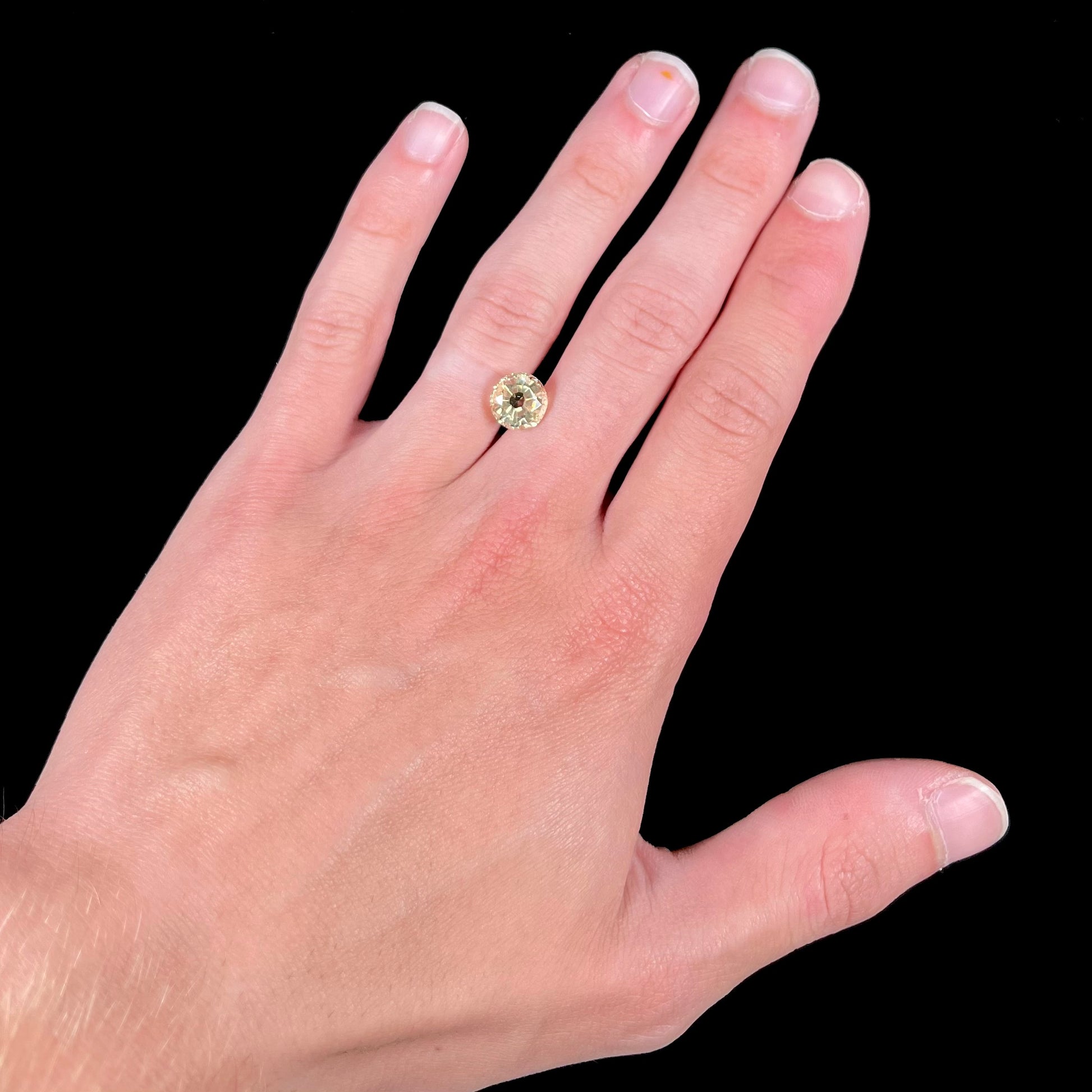 A loose, round brilliant cut citrine gemstone.  The stone is light yellow color.