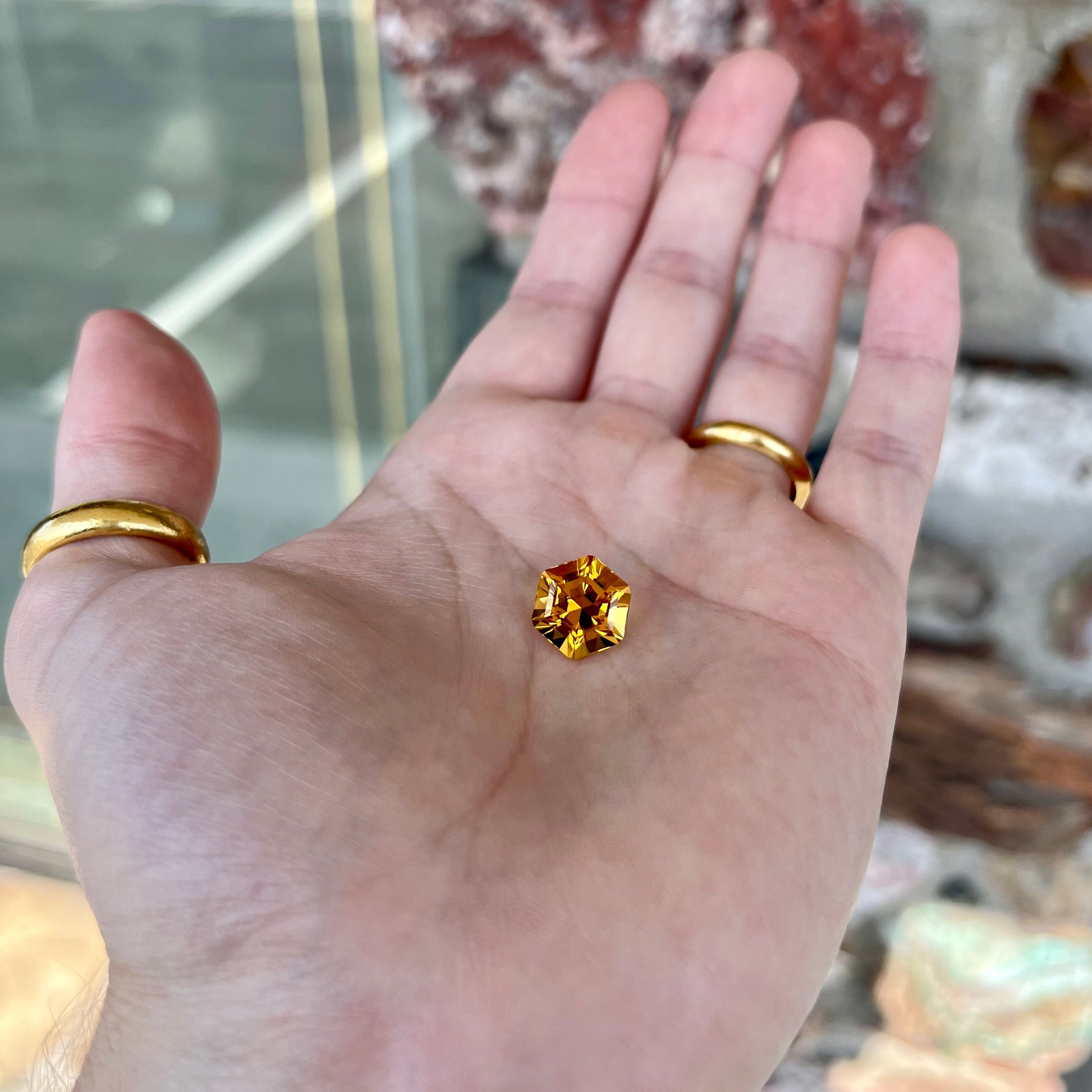 A loose, faceted hexagon cut citrine gem.  The stone is golden yellow color.