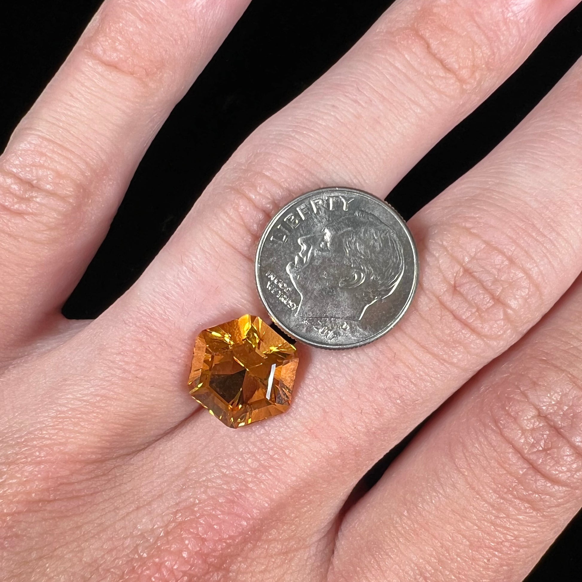 A loose, faceted hexagon cut citrine gem.  The stone is golden yellow color.