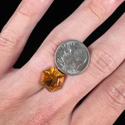 A loose, faceted hexagon cut citrine gem.  The stone is golden yellow color.