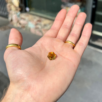 A loose, faceted hexagon cut citrine gem.  The stone is golden yellow color.
