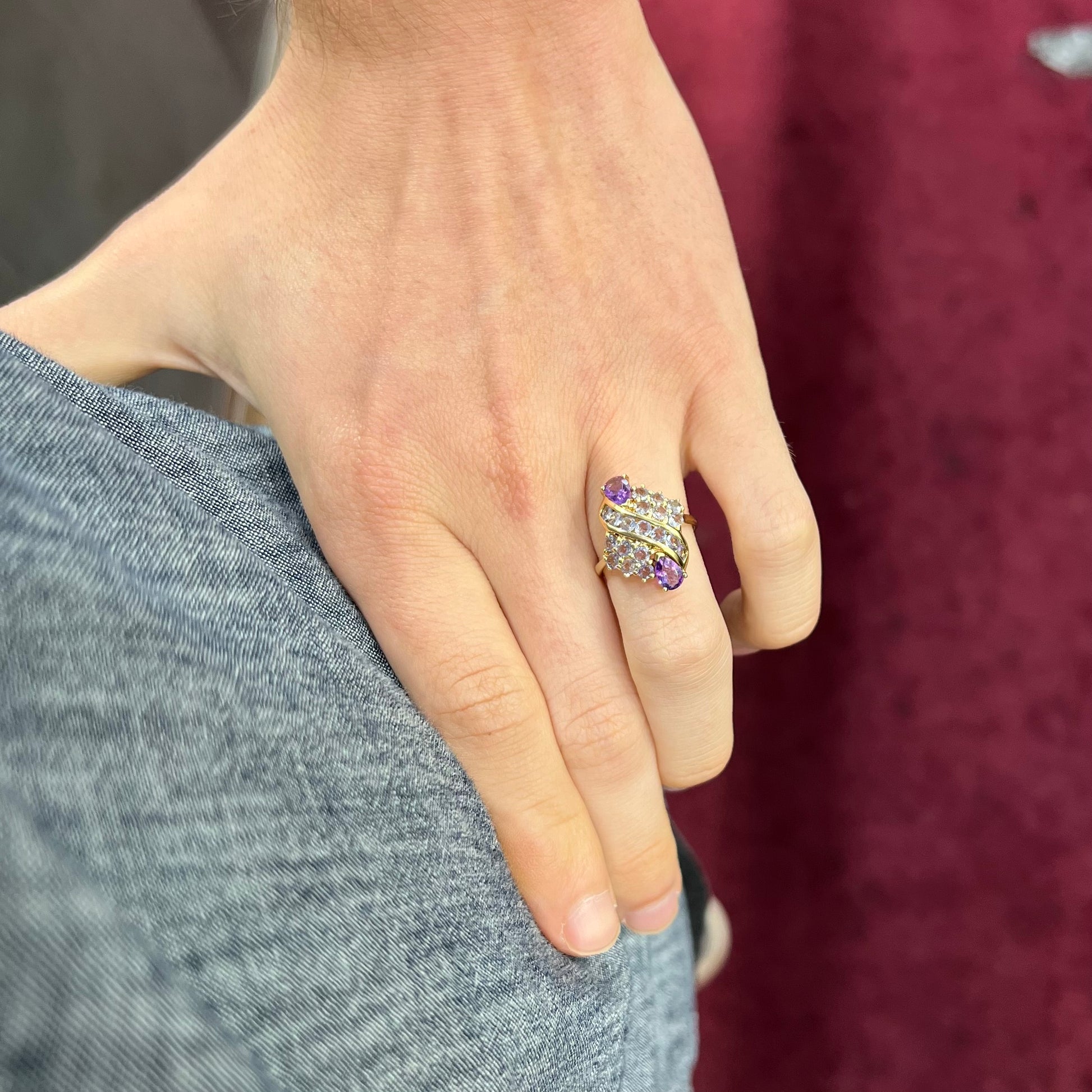 A ladies' gold ring set with a cluster of round tanzanites and two pear shaped amethyst accent stones.
