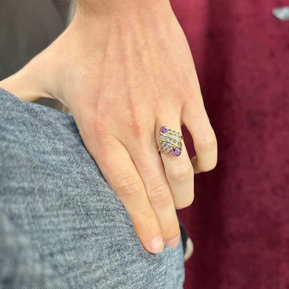 A ladies' gold ring set with a cluster of round tanzanites and two pear shaped amethyst accent stones.