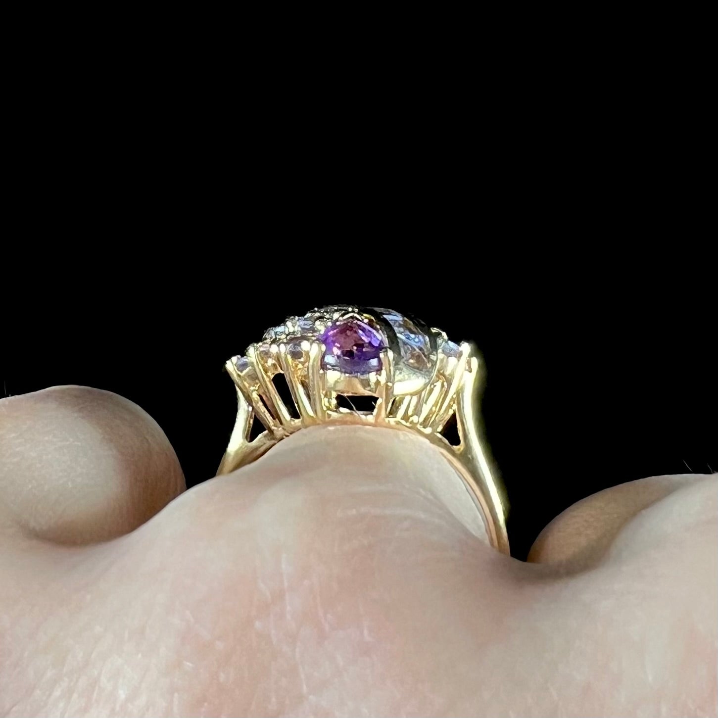 A ladies' gold ring set with a cluster of round tanzanites and two pear shaped amethyst accent stones.