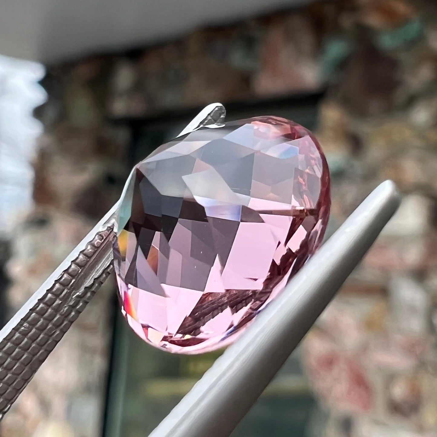 A loose, round brilliant checkerboard cut Zandrite gemstone.  The stone changes colors from greenish tan to purple.