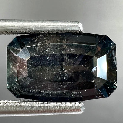 A loose, modified emerald cut, natural color change sapphire stone.  The stone shifts from black to blue to purple to green.