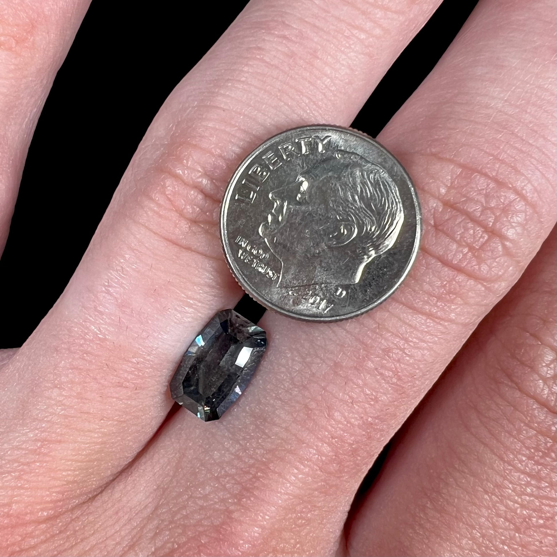A loose, modified emerald cut, natural color change sapphire stone.  The stone shifts from black to blue to purple to green.