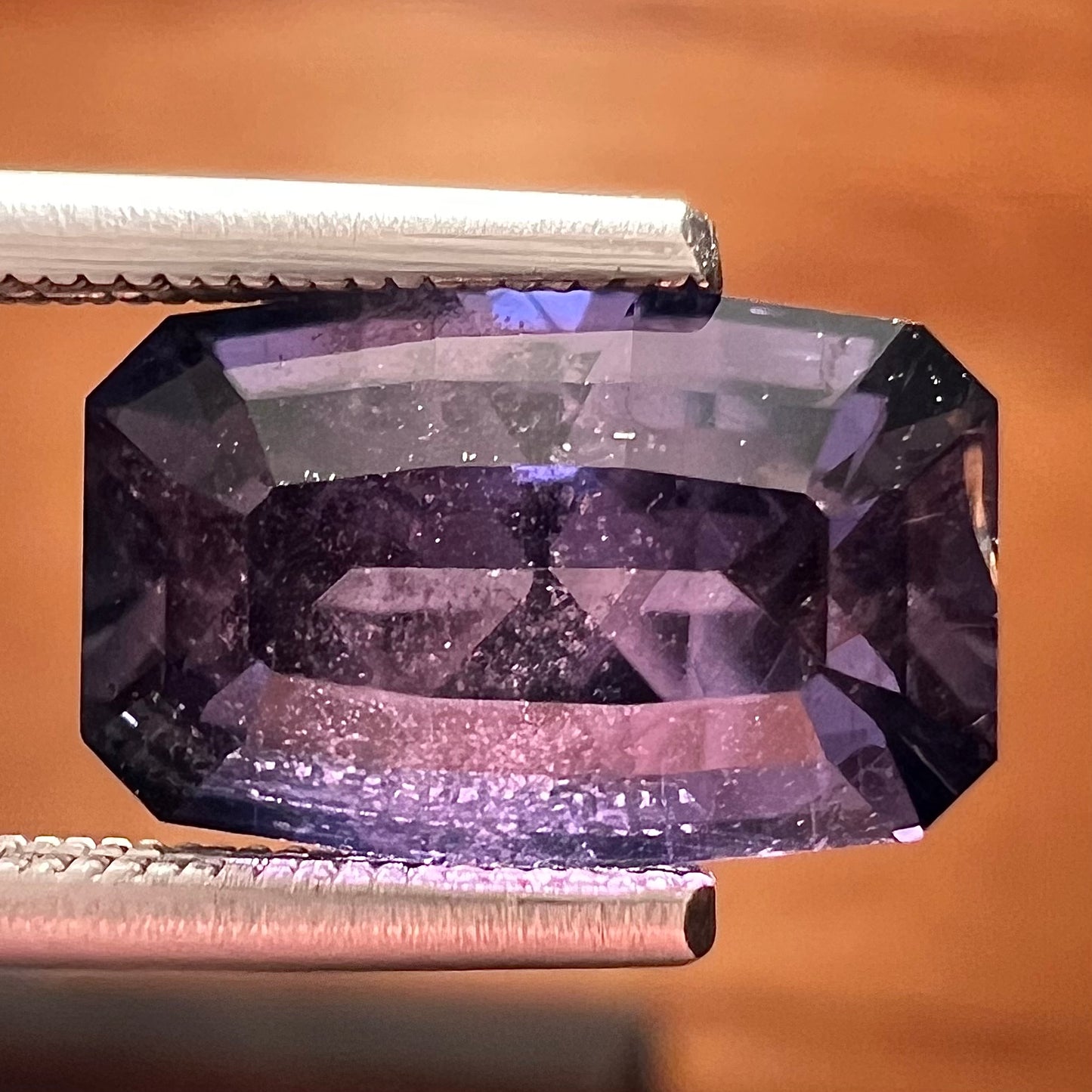 A loose, modified emerald cut, natural color change sapphire stone.  The stone shifts from black to blue to purple to green.