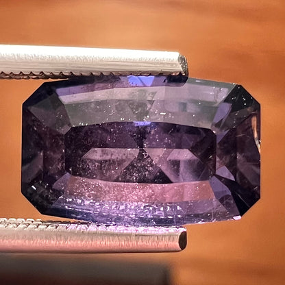 A loose, modified emerald cut, natural color change sapphire stone.  The stone shifts from black to blue to purple to green.