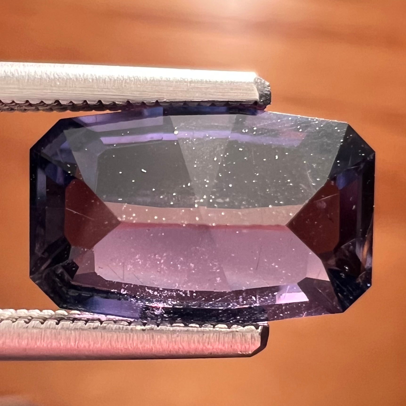 A loose, modified emerald cut, natural color change sapphire stone.  The stone shifts from black to blue to purple to green.