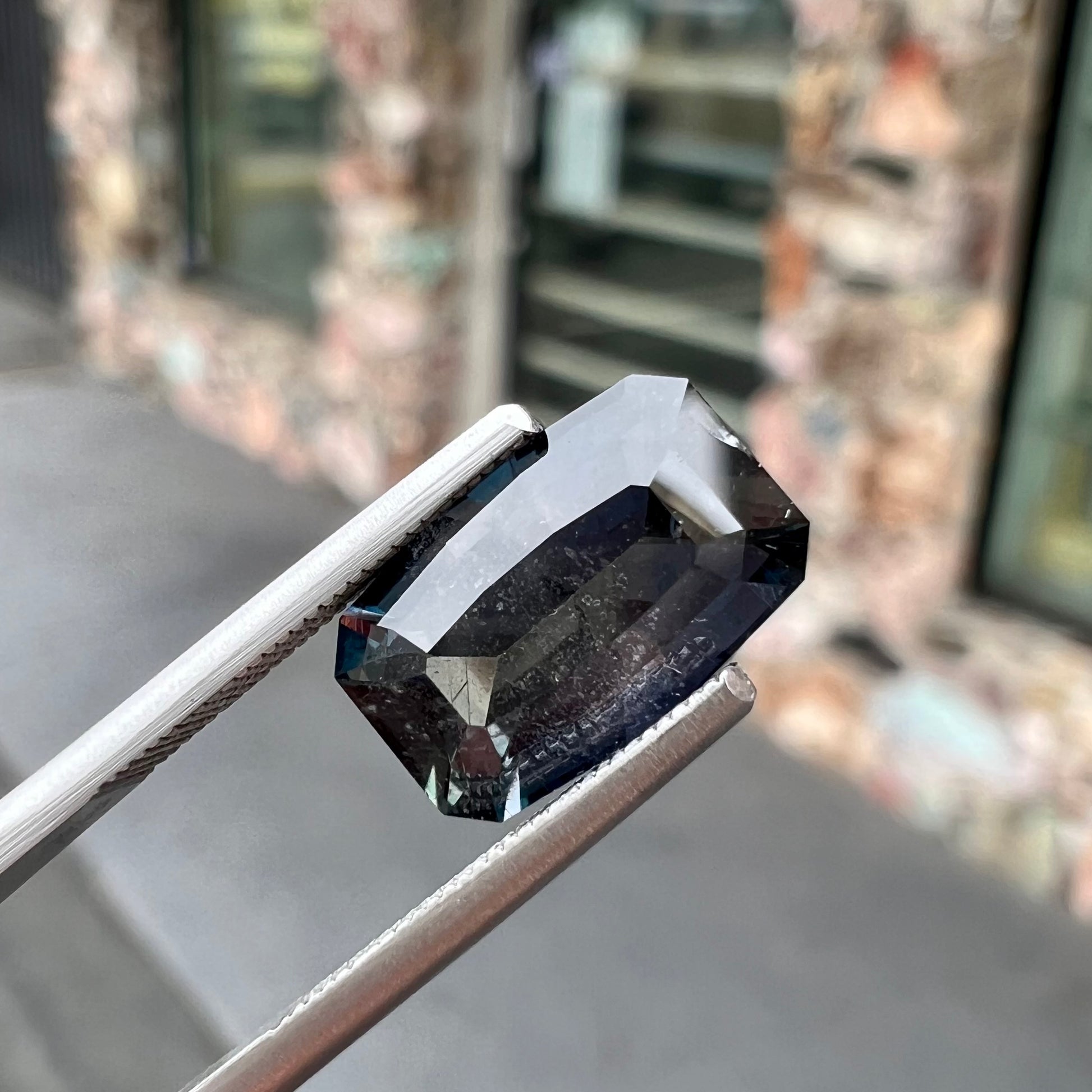 A loose, modified emerald cut, natural color change sapphire stone.  The stone shifts from black to blue to purple to green.