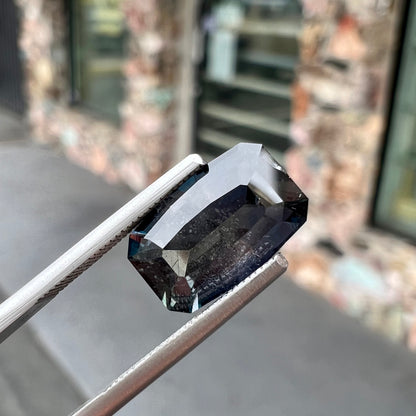 A loose, modified emerald cut, natural color change sapphire stone.  The stone shifts from black to blue to purple to green.