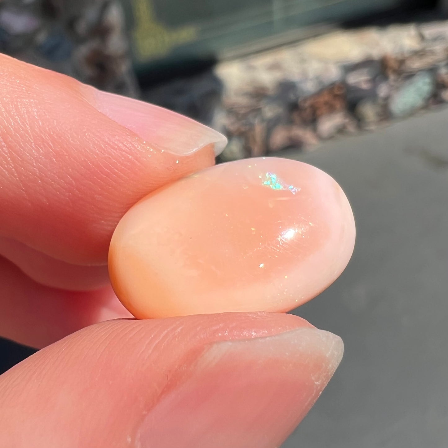 A loose, oval cabochon cut Peruvian opal stone.  The opal is a coral pink color.