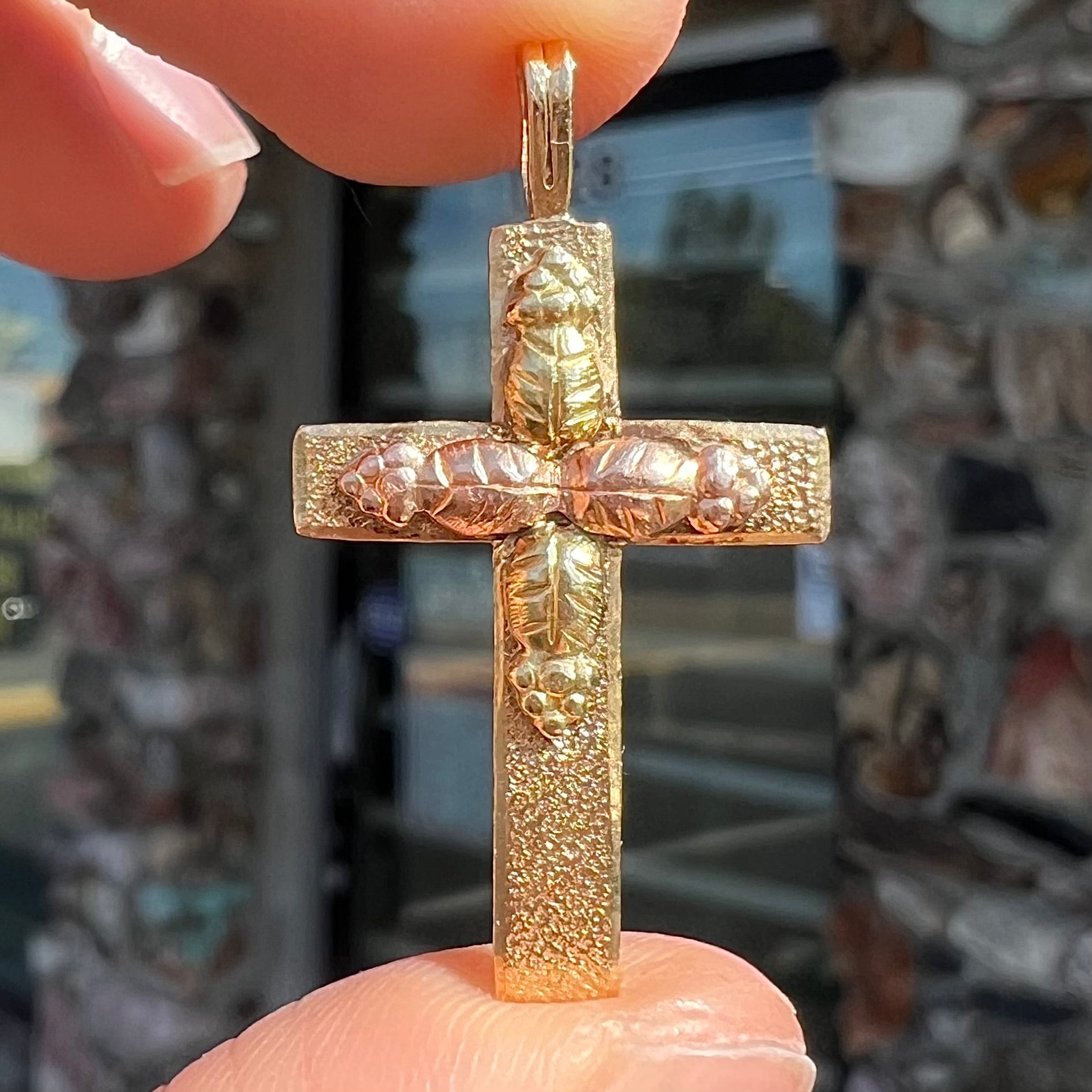 A cross made from yellow and rose gold Black Hills gold.  The cross features a leaf design.