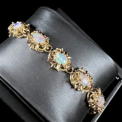 A ladies' yellow gold bracelet set with natural, oval cabochon cut white crystal opals.