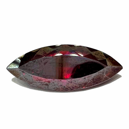 A loose, marquise cut cuprite gemstone.  The stone is a deep, crimson red color.
