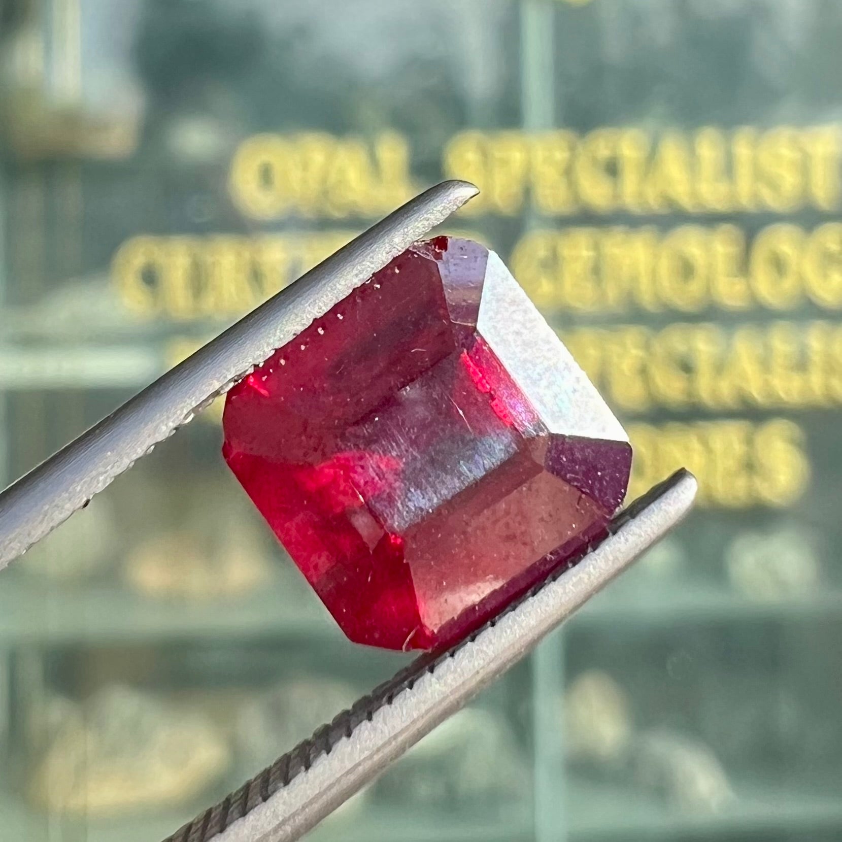 A loose, modified Asscher cut cuprite gemstone.  The stone is a deep, crimson red color and has several chips along the girdle.