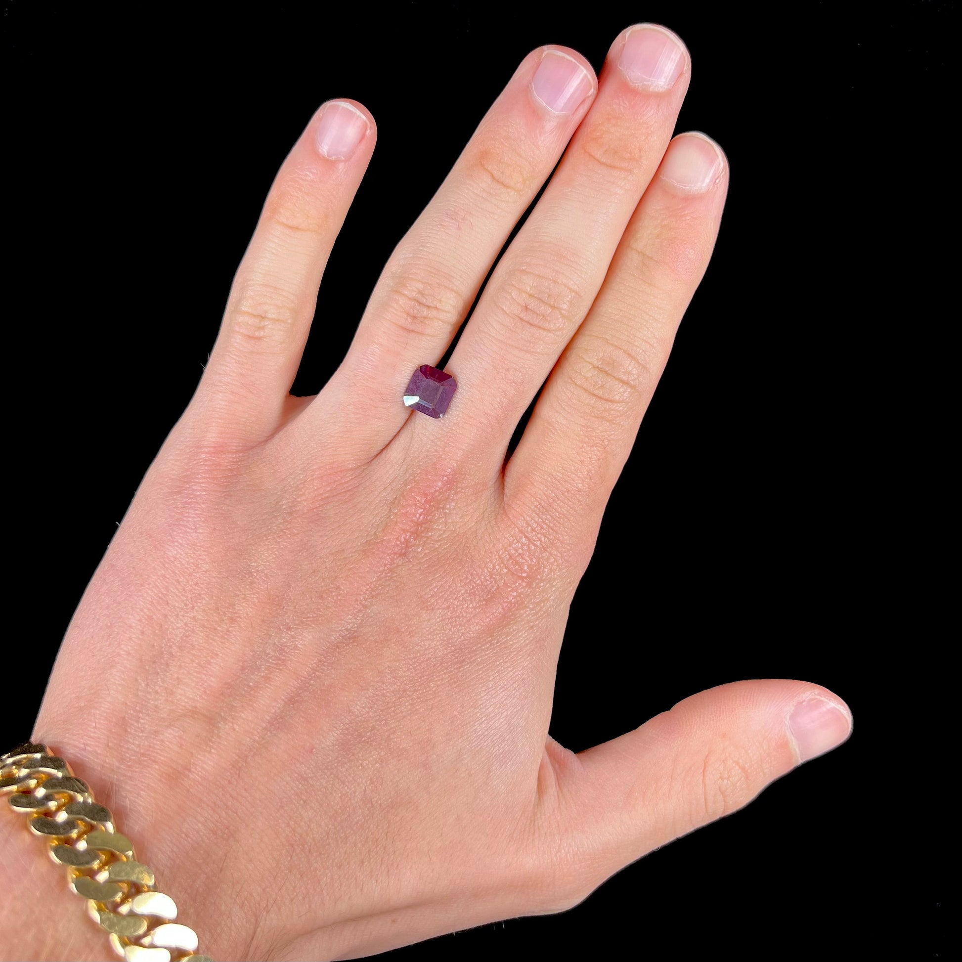 A loose, modified Asscher cut cuprite gemstone.  The stone is a deep, crimson red color and has several chips along the girdle.