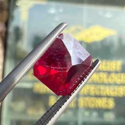 A loose, modified Asscher cut cuprite gemstone.  The stone is a deep, crimson red color and has several chips along the girdle.