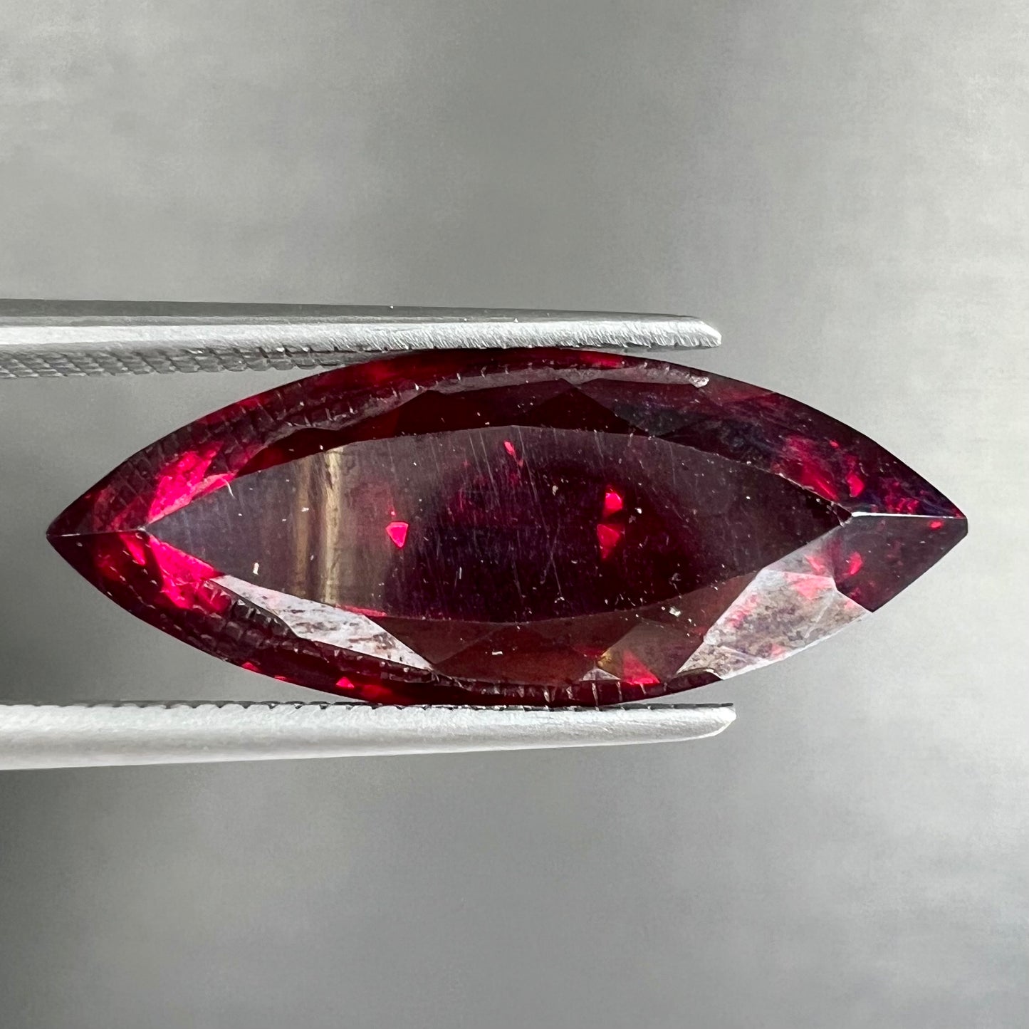 A loose, marquise cut cuprite gemstone.  The stone is a deep, crimson red color.