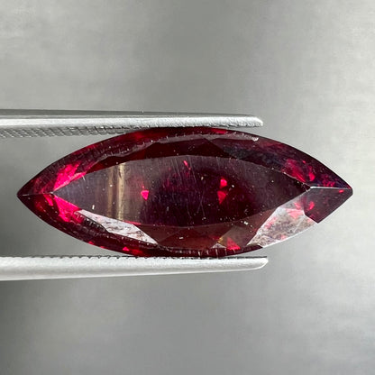 A loose, marquise cut cuprite gemstone.  The stone is a deep, crimson red color.